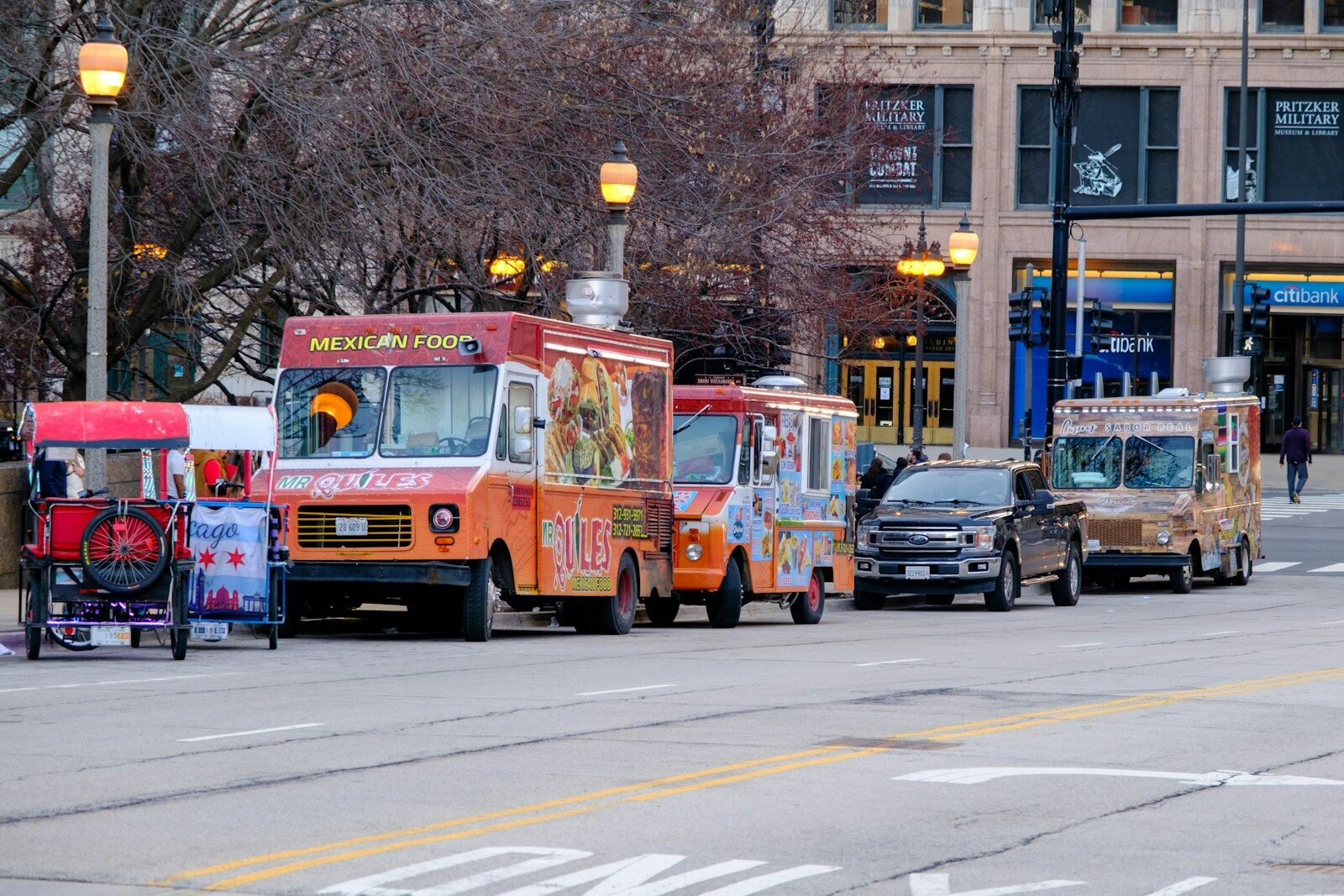 Food trucks and a pedicab parked on a city street in Chicago